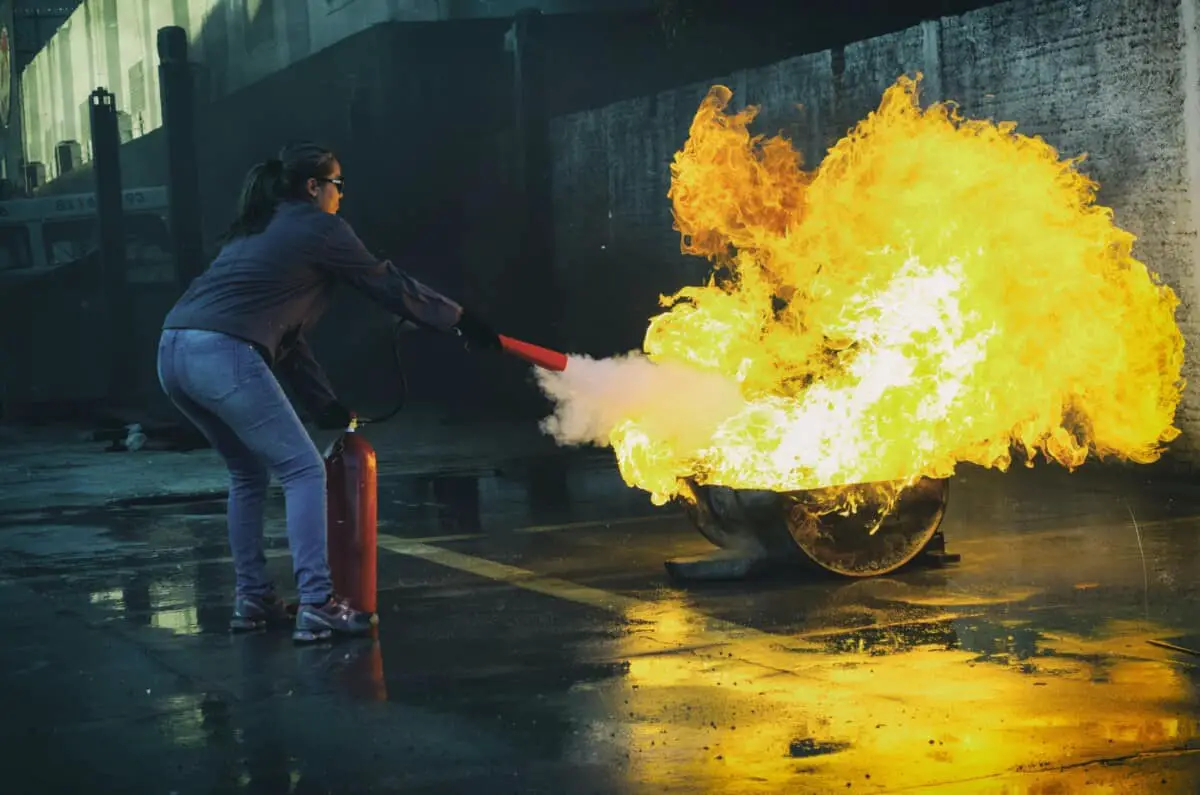 adult using fire extinguisher on fire
